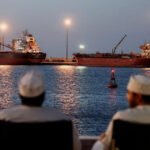 مواطنان عُمانيان جالسان أمام ناقلات في مضيق هرمز